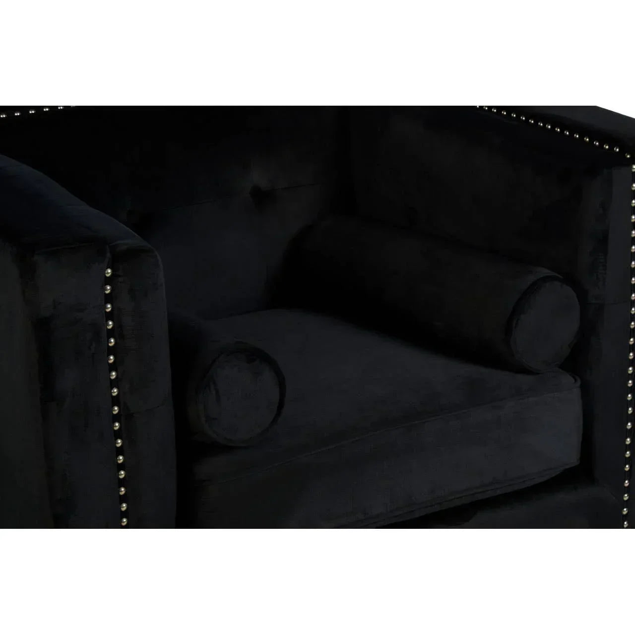 Black velvet armchair with silver stud trim and cylindrical bolster cushions