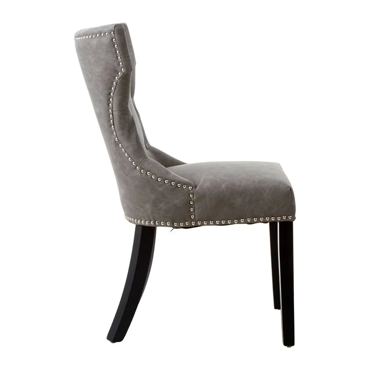 Grey upholstered dining chair with silver stud detailing and black wooden legs, side view