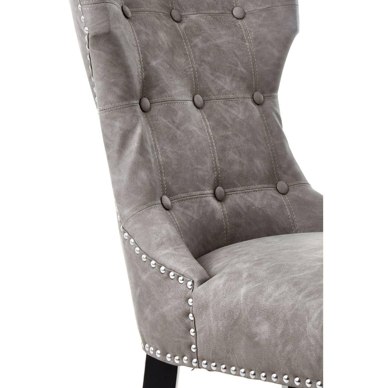 Grey upholstered dining chair with button tufting and silver stud detailing
