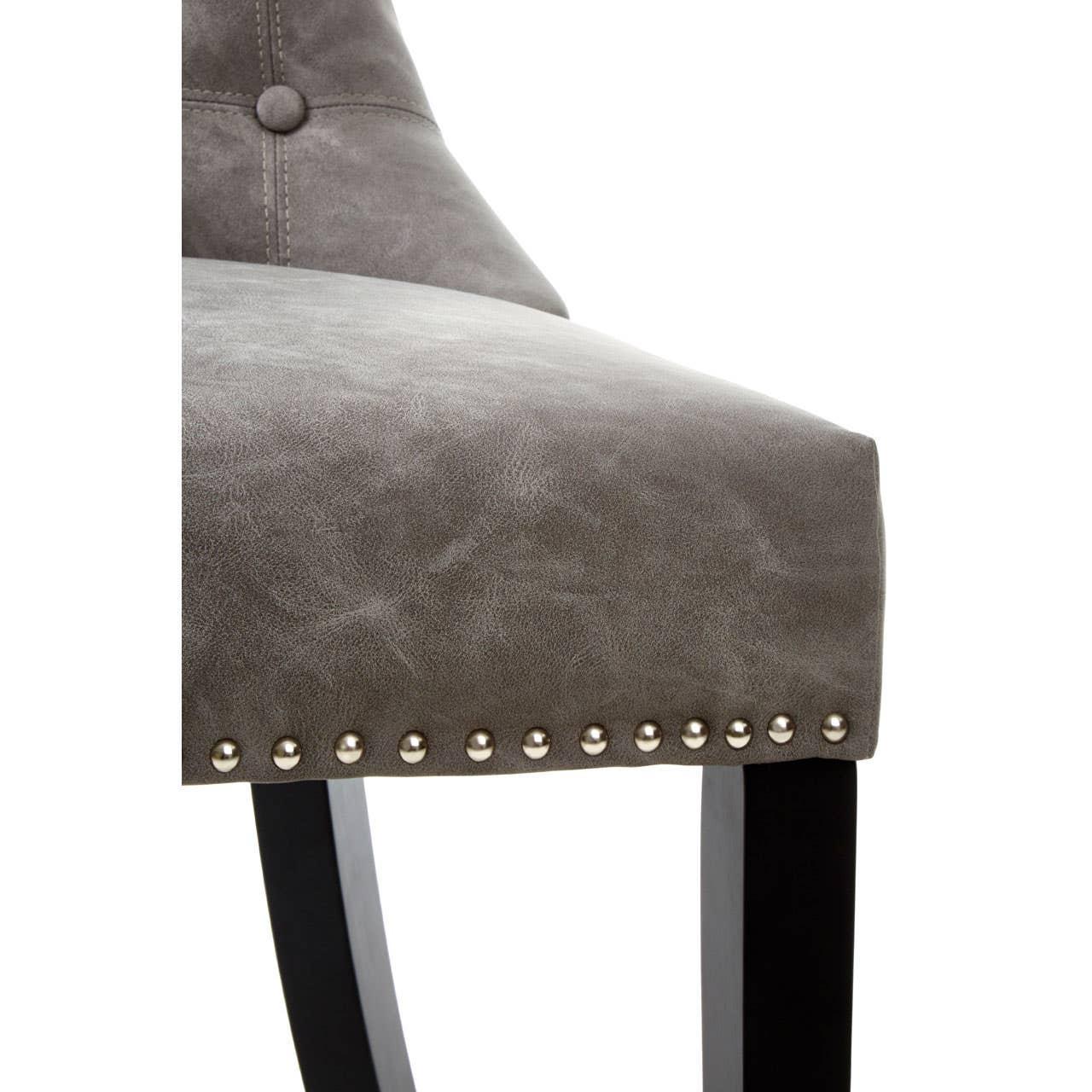 Grey dining chair close-up with button detail and metal stud trim on seat edge