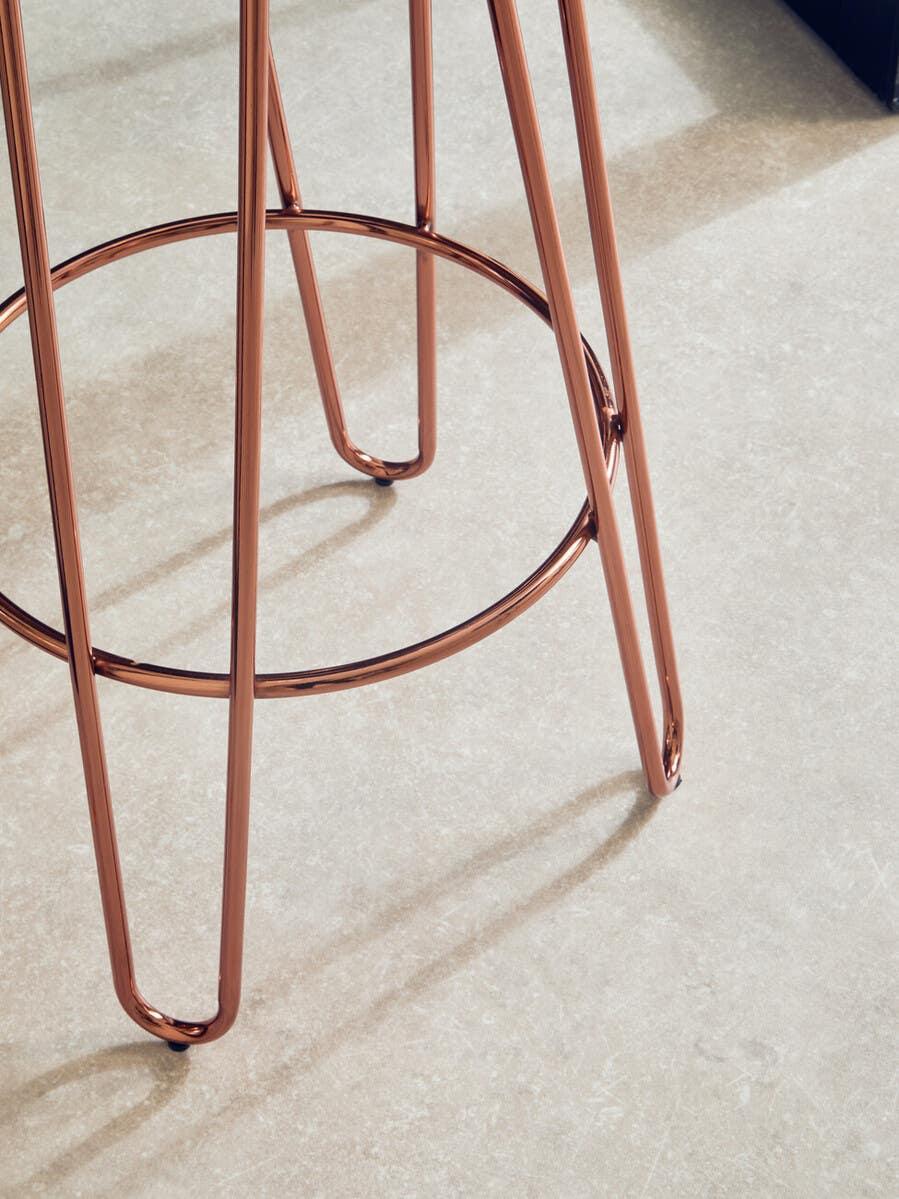 Copper metal stool legs on light stone tile floor, close up of modern furniture detail