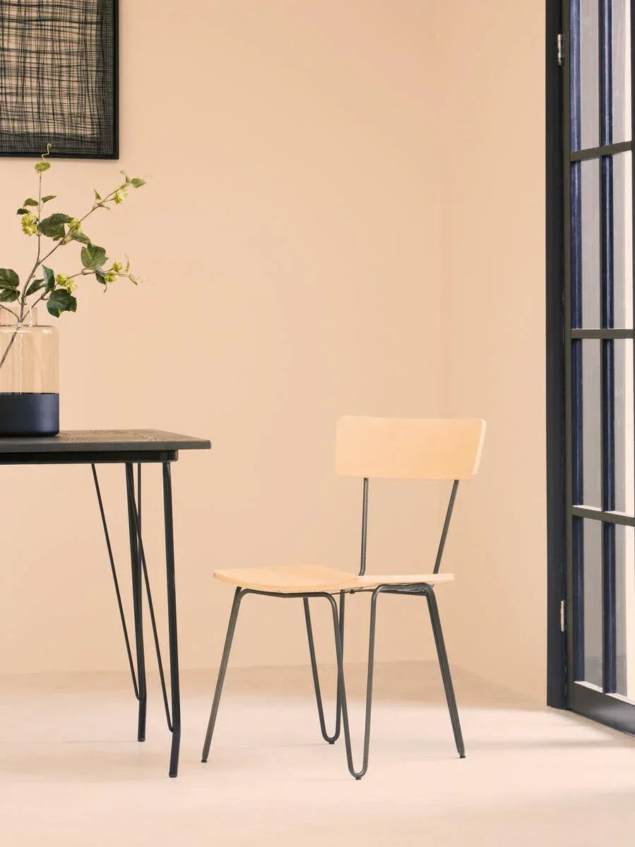 Light wood dining chair with black metal legs in minimalist room beside glass door