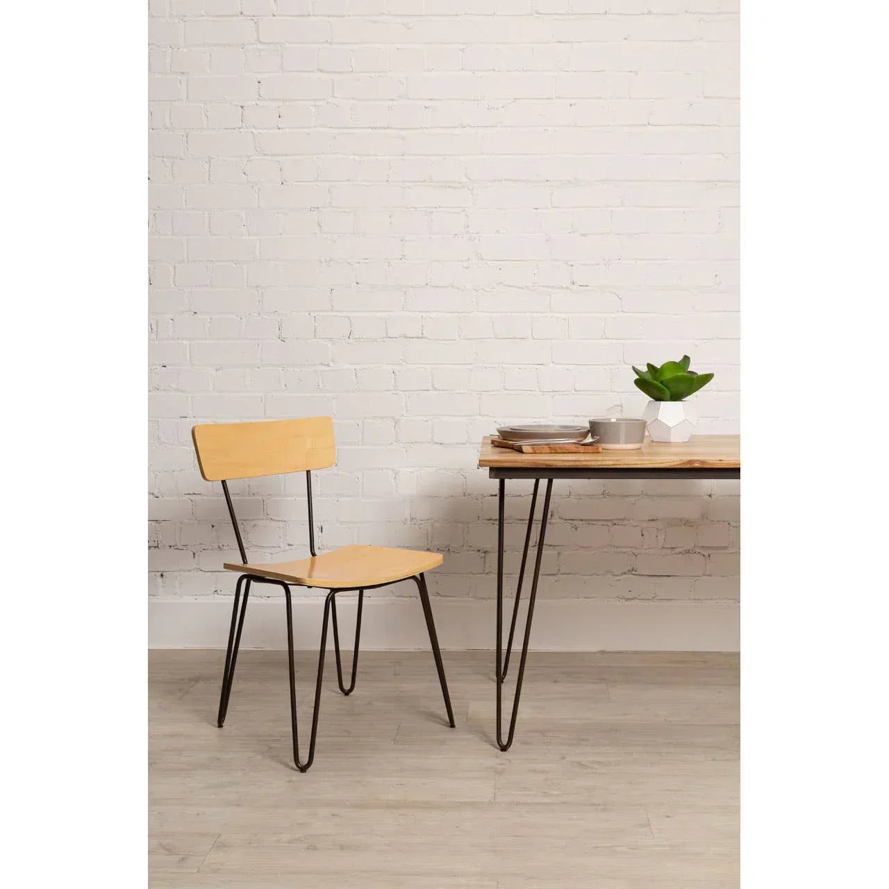 Light wood dining chair with black metal legs beside a matching table on laminate flooring