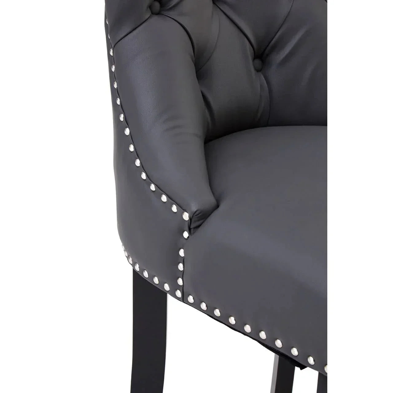 Close-up of black leather dining chair with button-tufted back and silver stud detailing