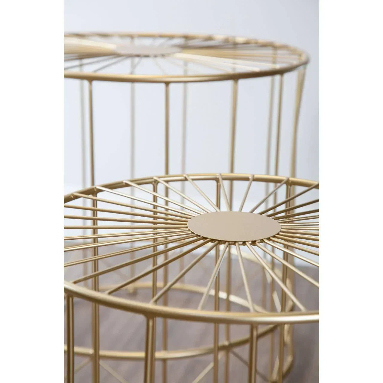Gold metal cage side tables with round tops and open geometric frame on wood floor