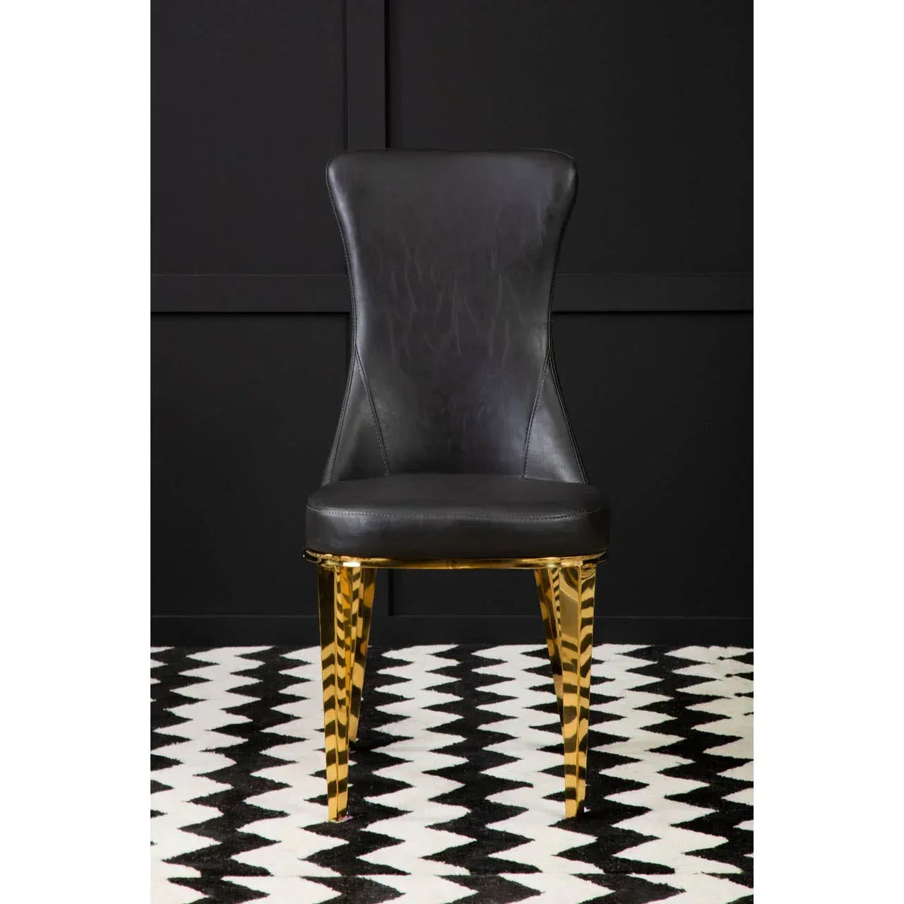 Black leather dining chair with gold metal legs on geometric monochrome rug