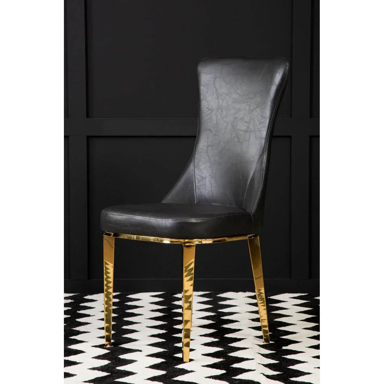 Black leather dining chair with gold metal legs on black and white geometric rug