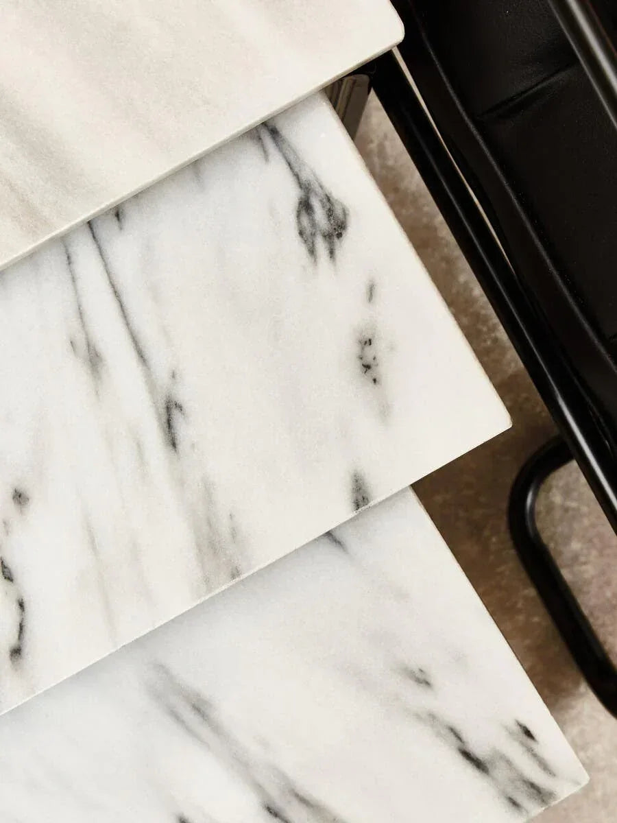 Stacked white marble table tops with black metal legs, close up of surface detail