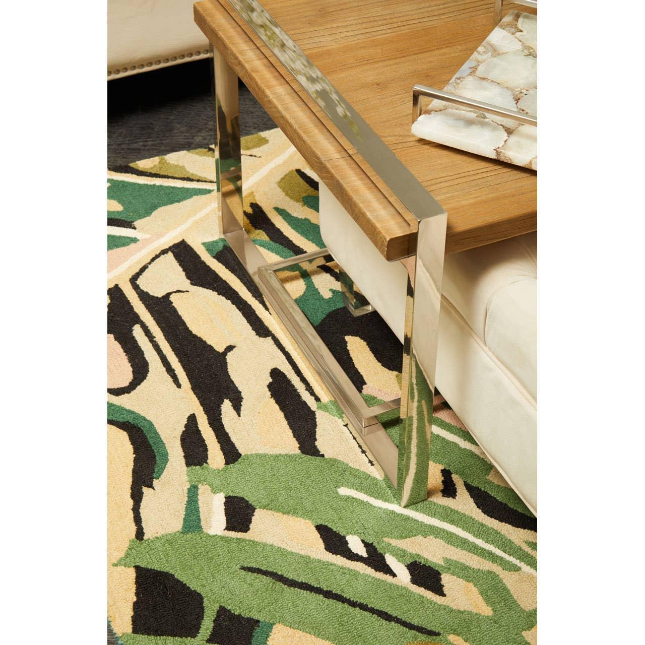 Modern wood coffee table with chrome legs on abstract green and beige patterned rug