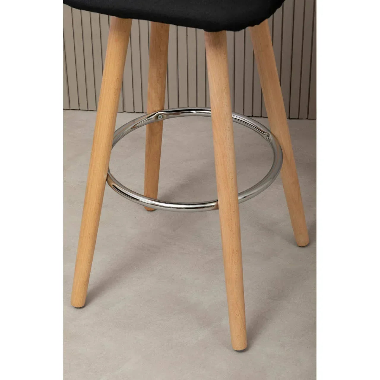 Bar stool with wooden legs and chrome footrest on light tiled floor
