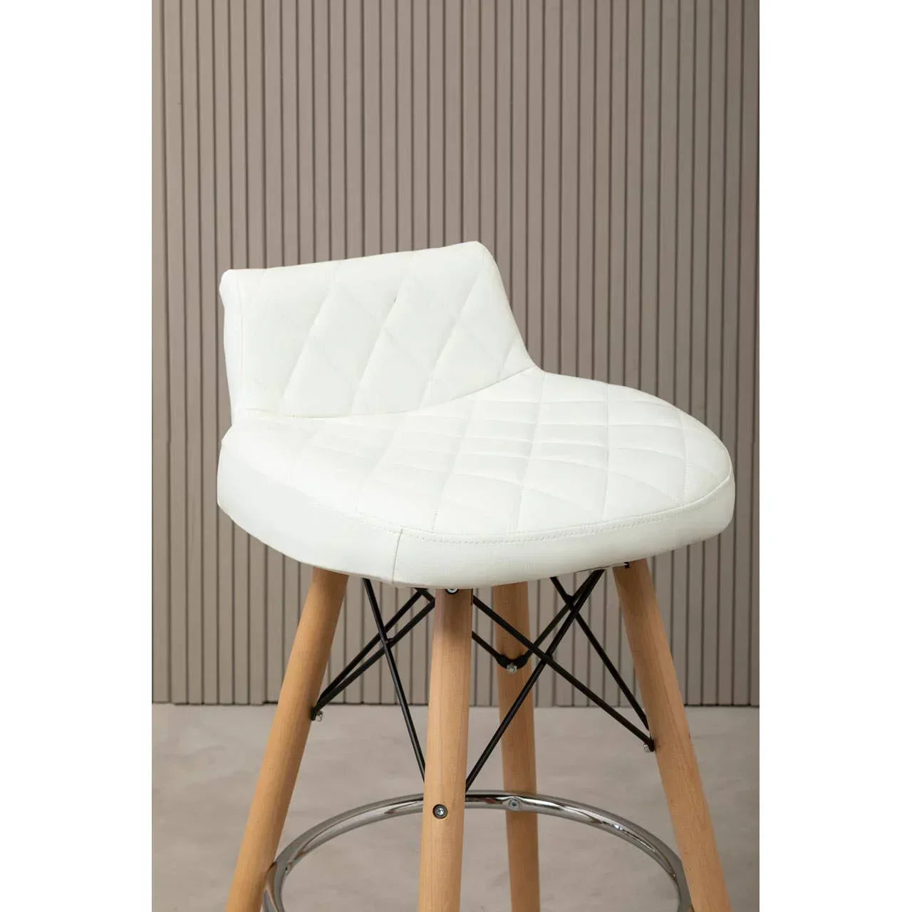 White bar stool with quilted seat, wooden legs and chrome footrest against panelled wall