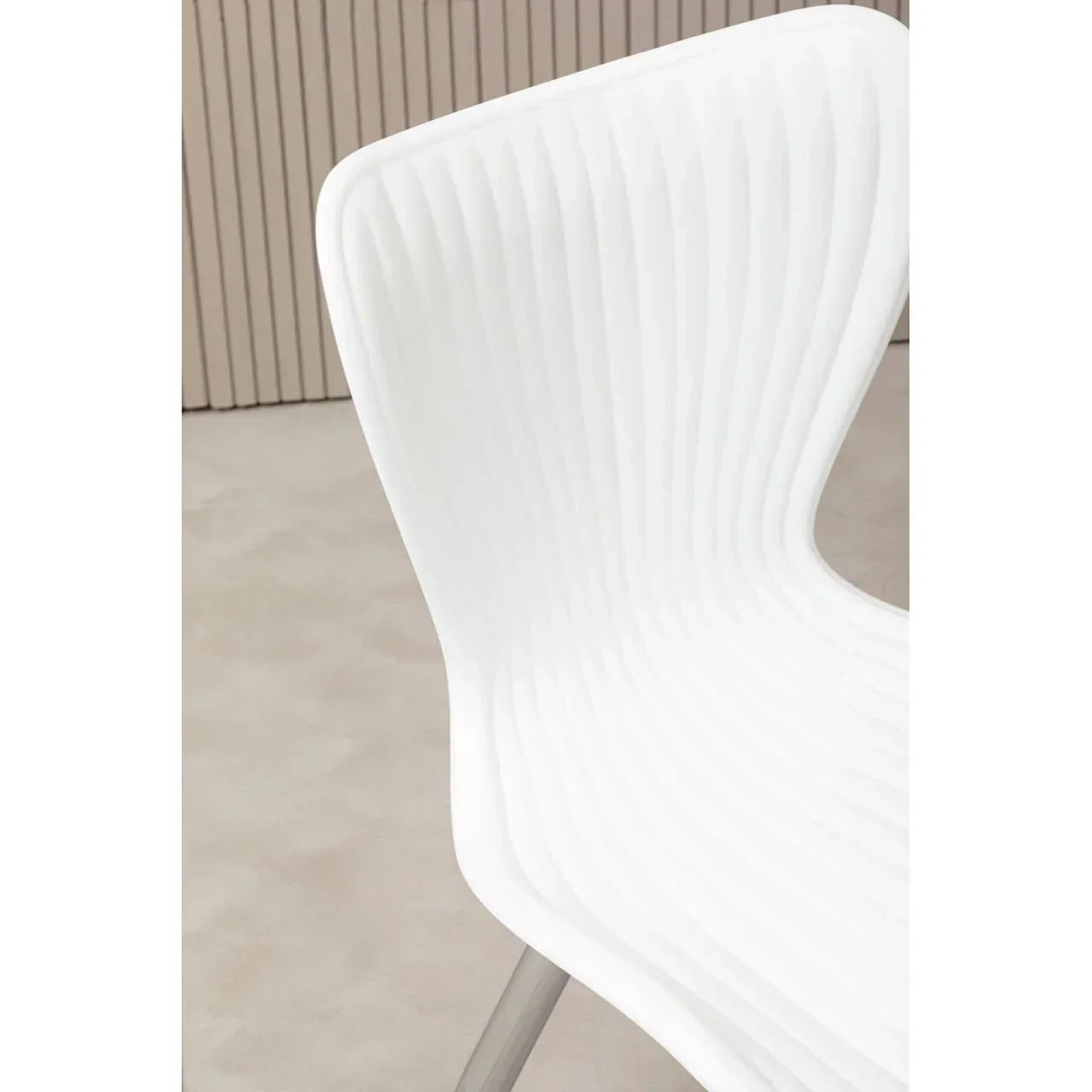 White modern dining chair with ribbed plastic backrest and metal legs, close side view