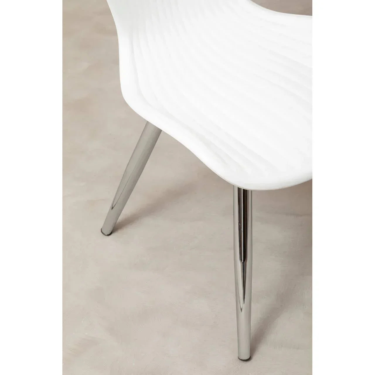 White dining chair with contoured seat and chrome metal legs, close-up view