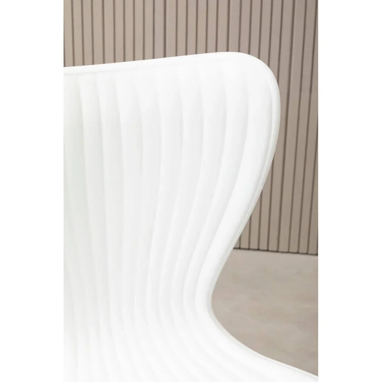 White molded plastic chair with curved backrest and ribbed texture, close-up view