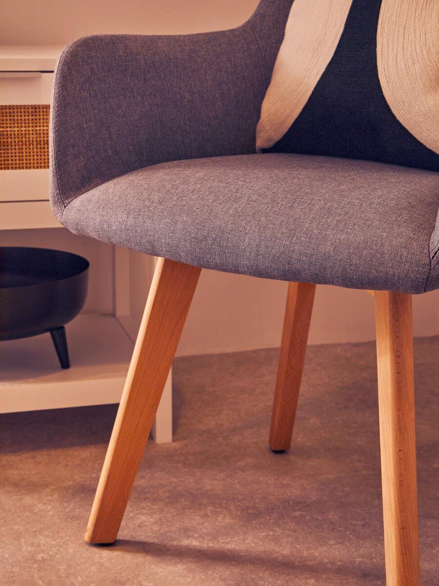 Grey fabric accent chair with wooden legs and cushion in modern living room setting