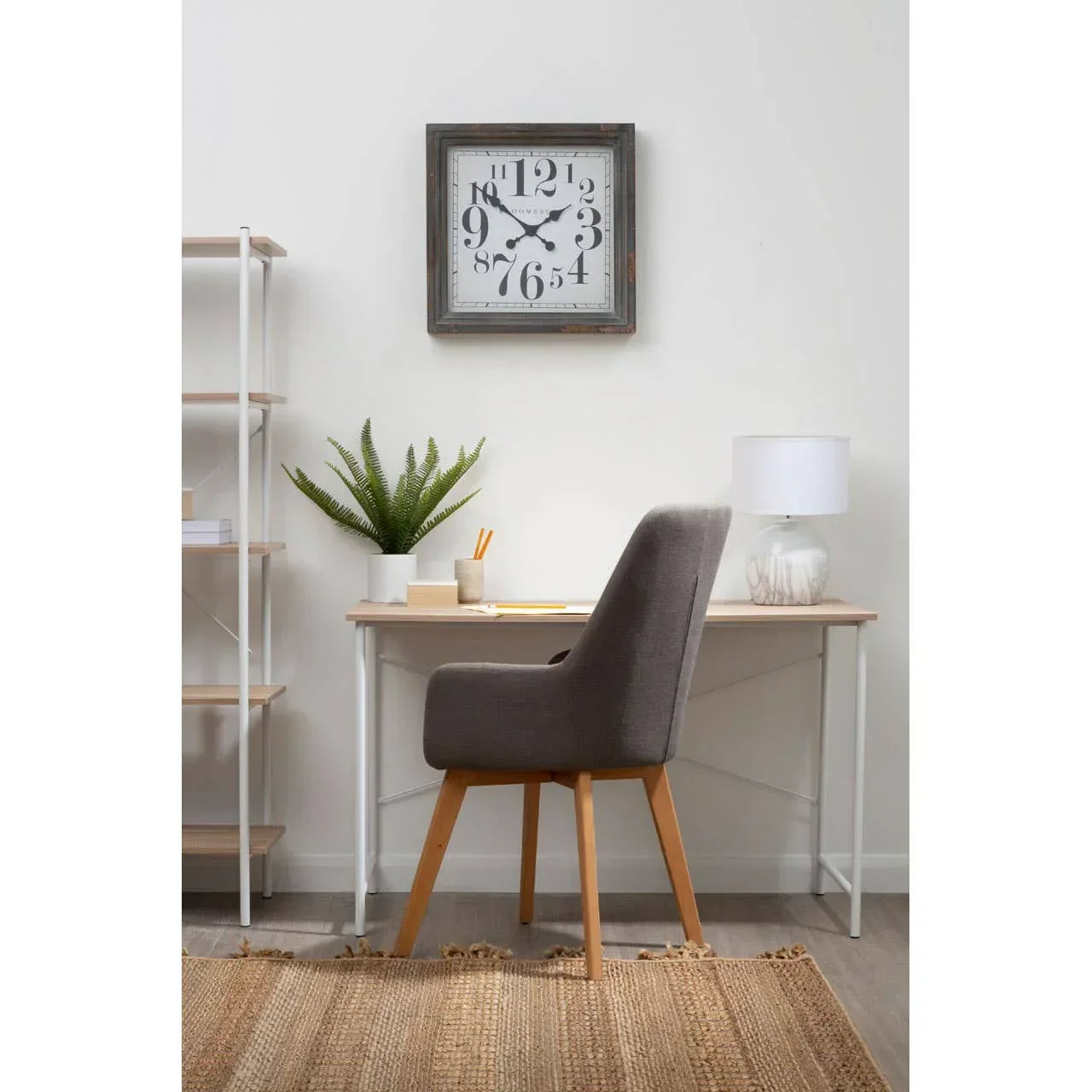 Grey upholstered accent chair at modern office desk with lamp and plant