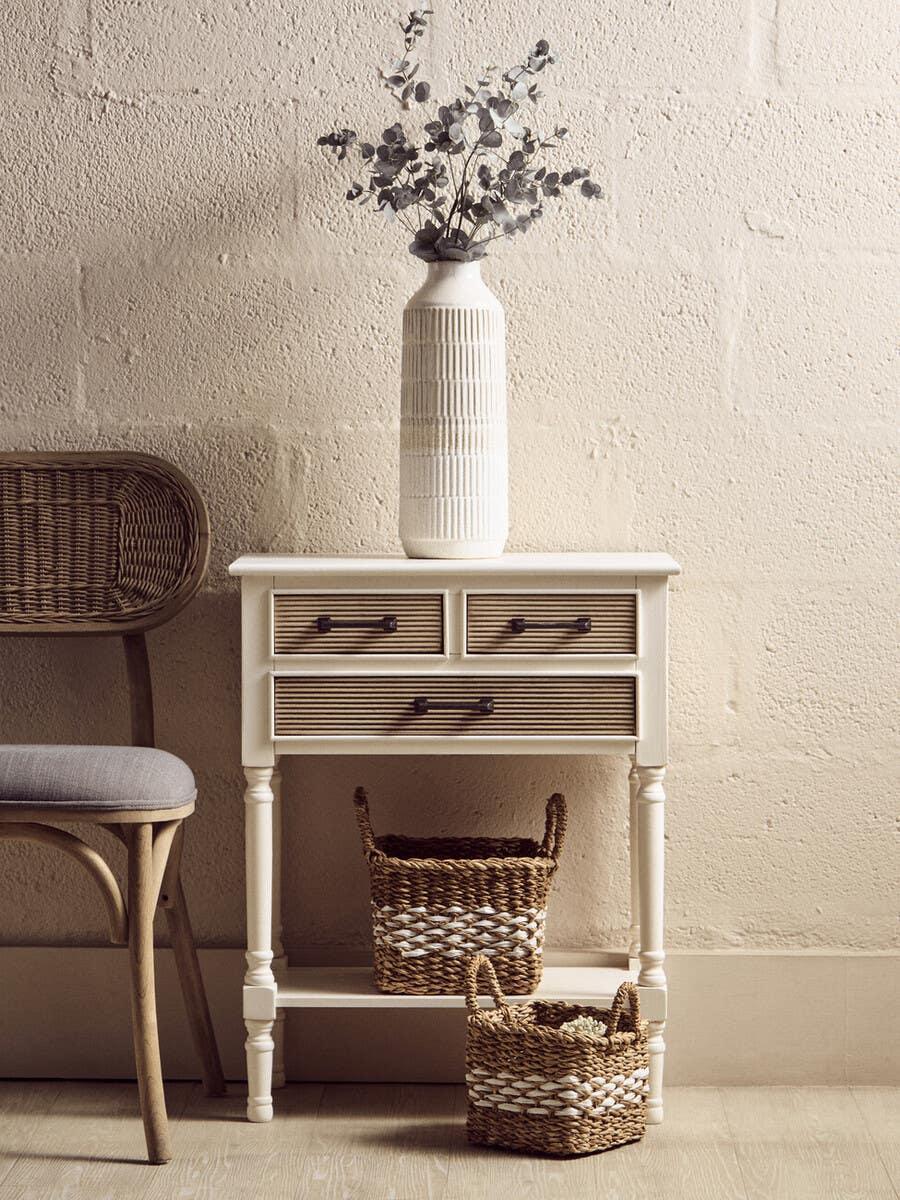 Cream hallway console table with drawers, wicker baskets and ceramic vase with foliage