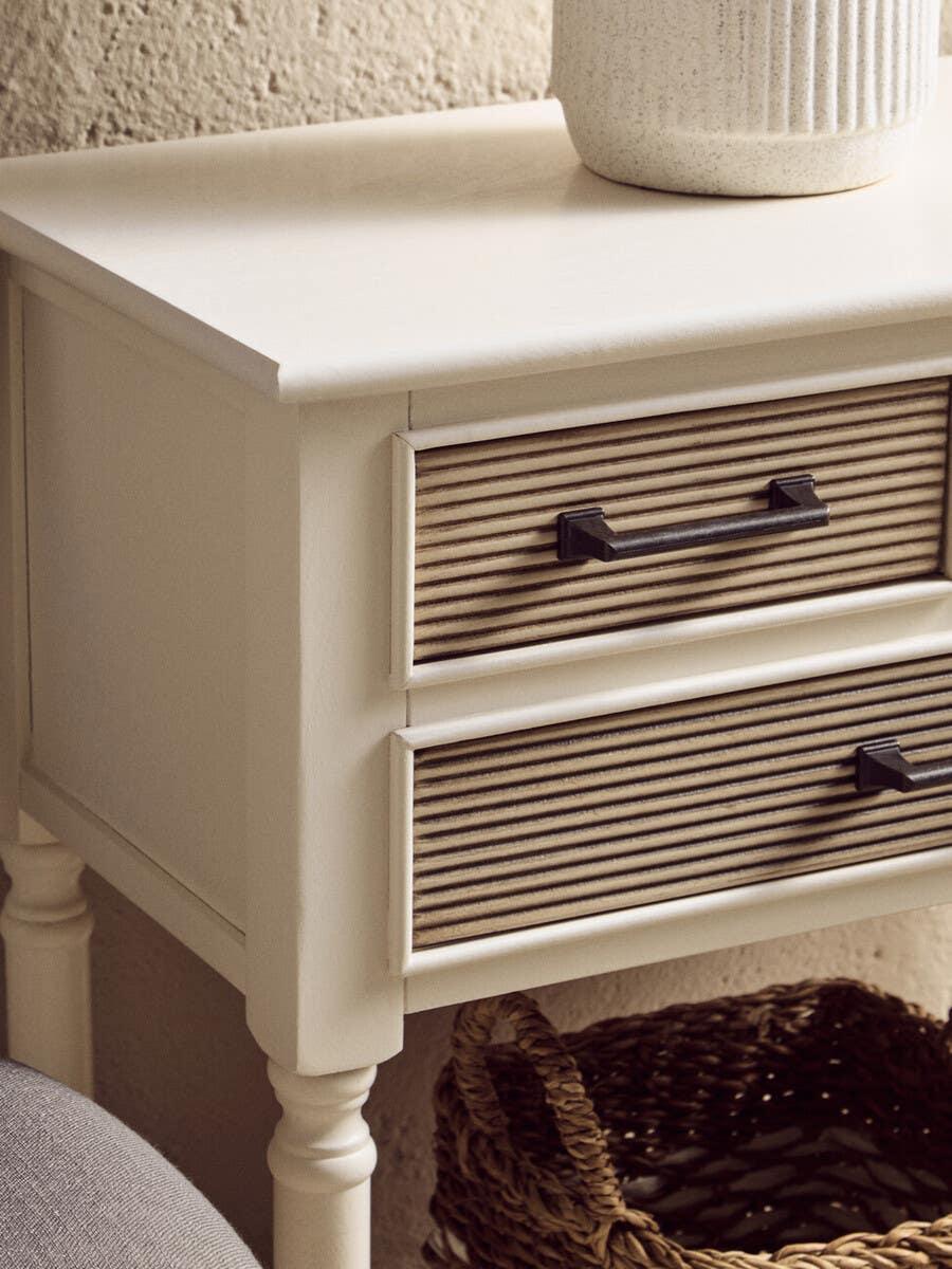 Cream bedside table with ribbed wood drawers and black handles, wicker basket underneath