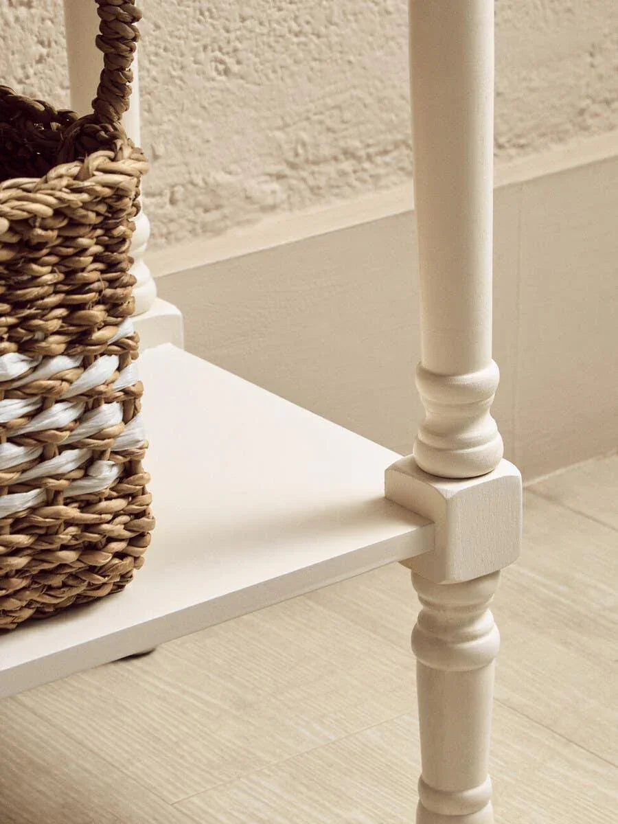 Close view of cream wooden table leg and corner shelf with woven seagrass storage basket