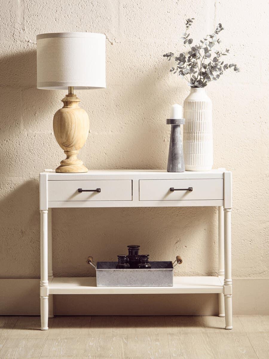 Cream console table with two drawers, wooden lamp, ceramic vase and candle holder on top
