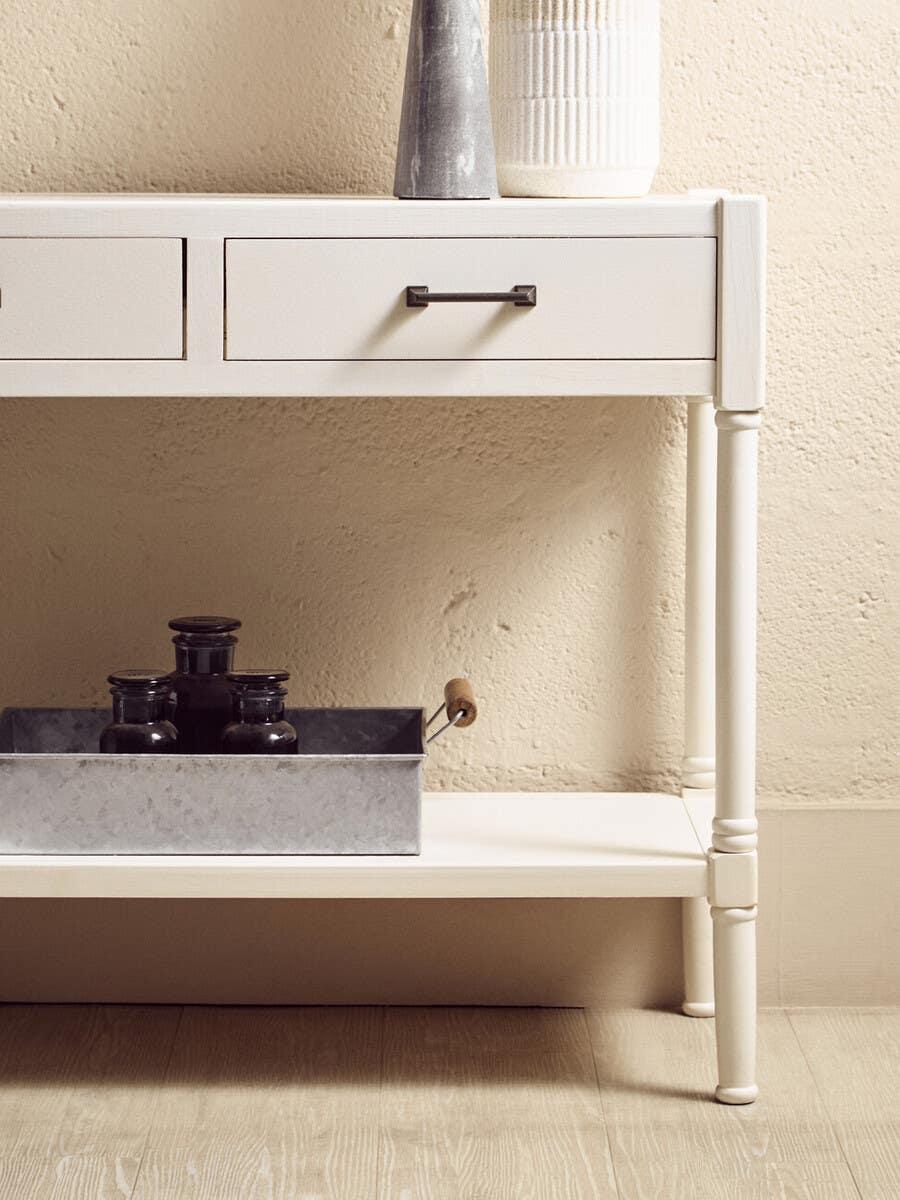 White console table with two drawers, lower shelf and metal tray with glass jars