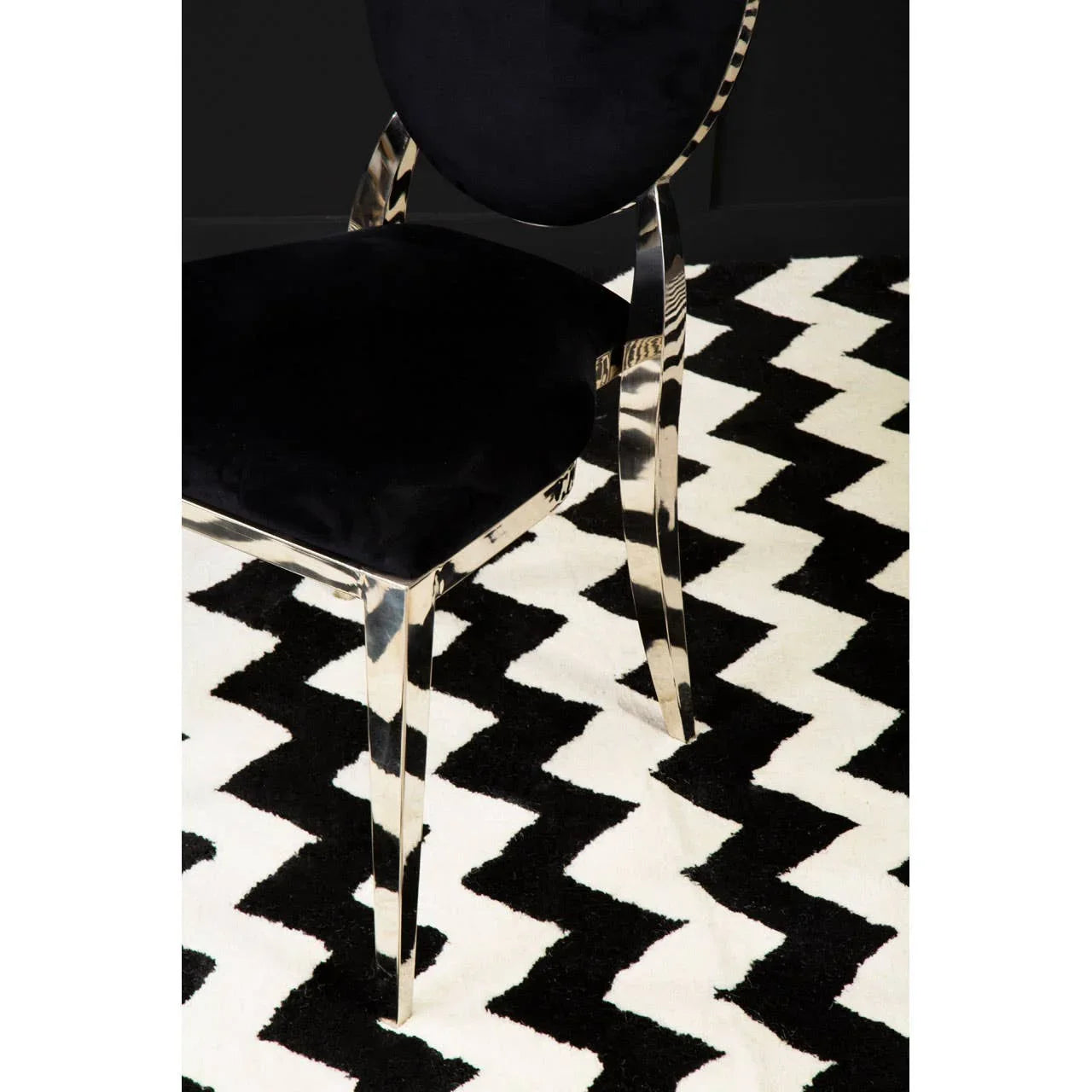 Black velvet dining chair with chrome legs on black and white zigzag patterned rug