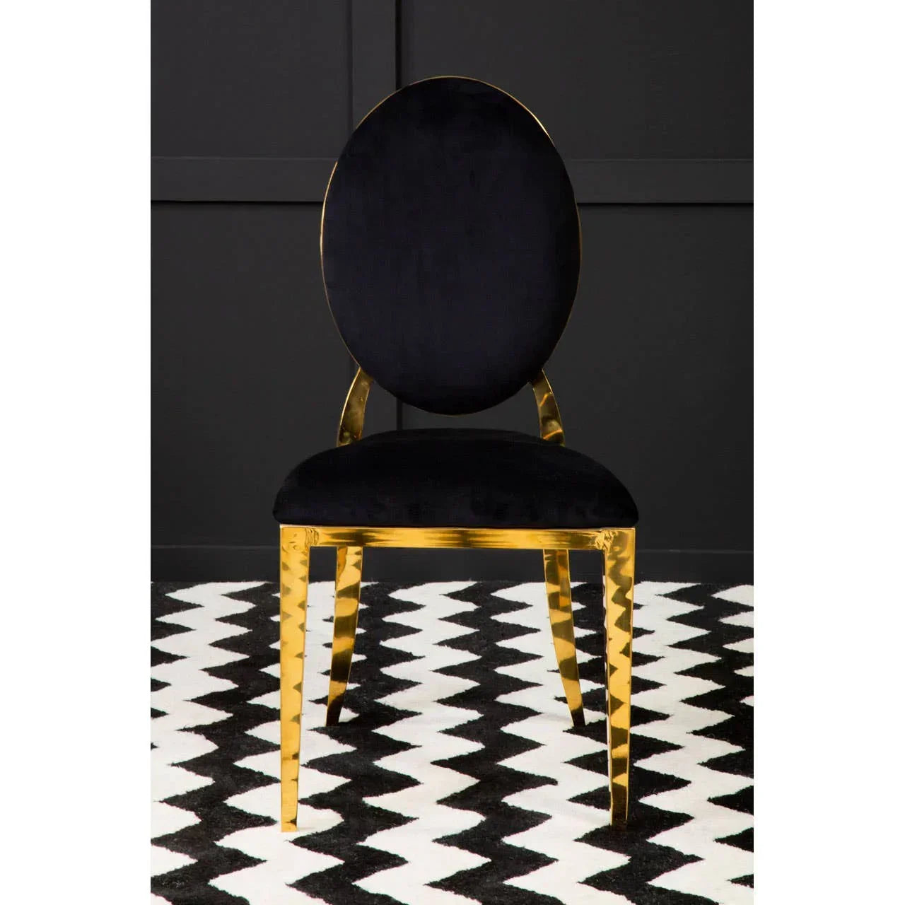 Black velvet dining chair with gold metal legs on chevron rug