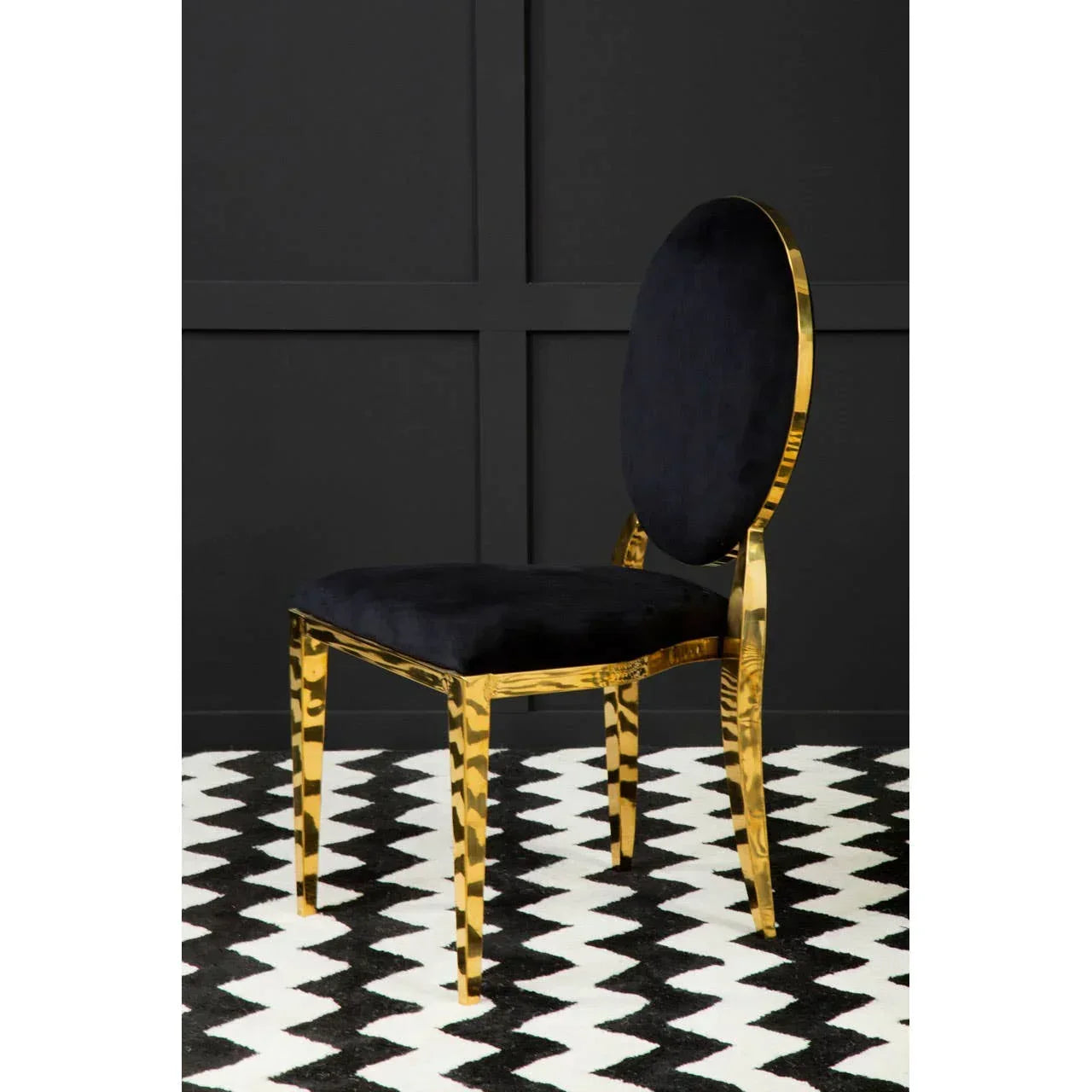 Black velvet dining chair with gold metal frame on geometric patterned rug