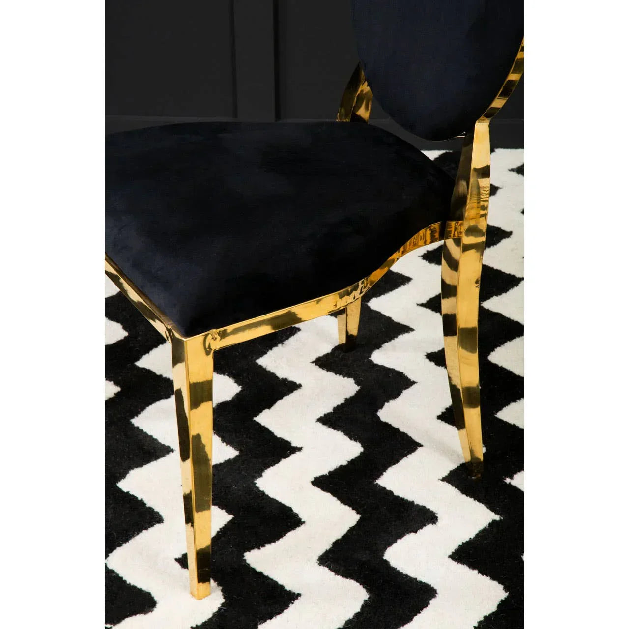Black velvet dining chair with gold legs on a chevron patterned rug