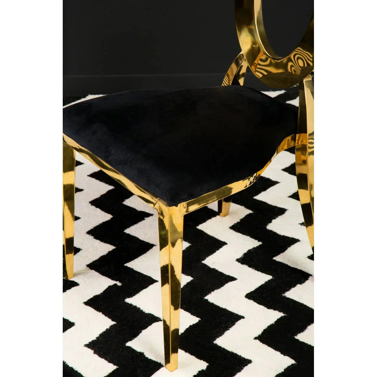 Gold dining chair with black velvet seat on black and white zigzag rug