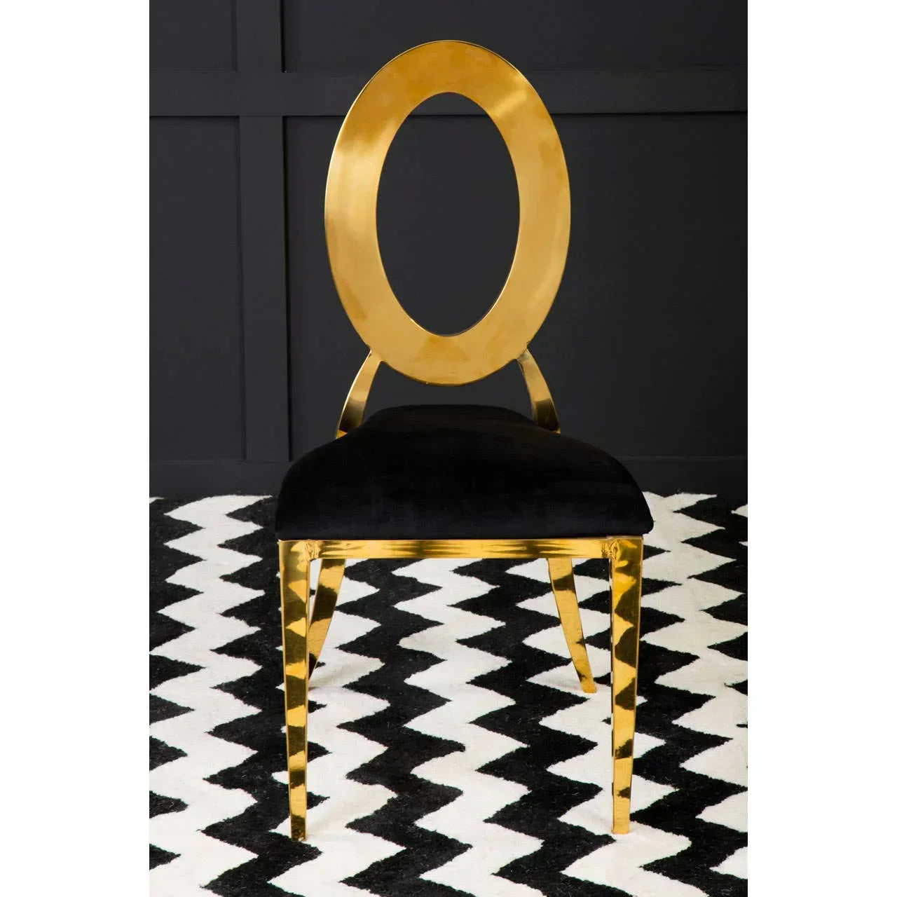 Gold dining chair with oval backrest and black velvet seat on chevron rug