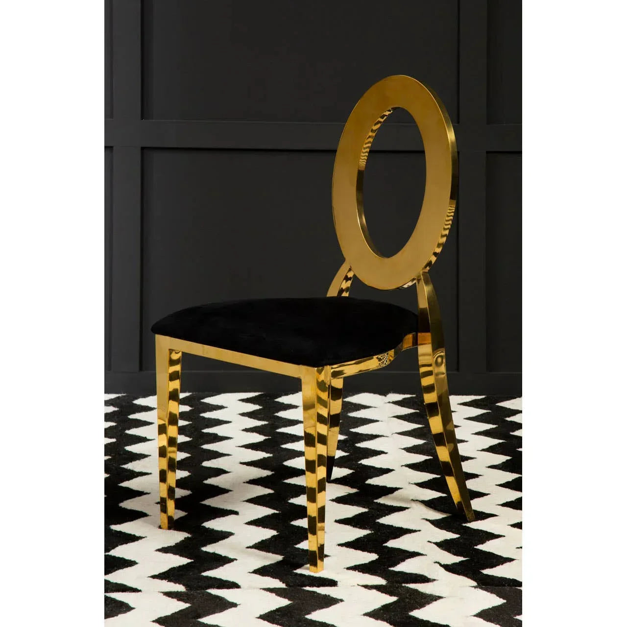 Gold metal dining chair with black seat cushion on geometric rug in modern room