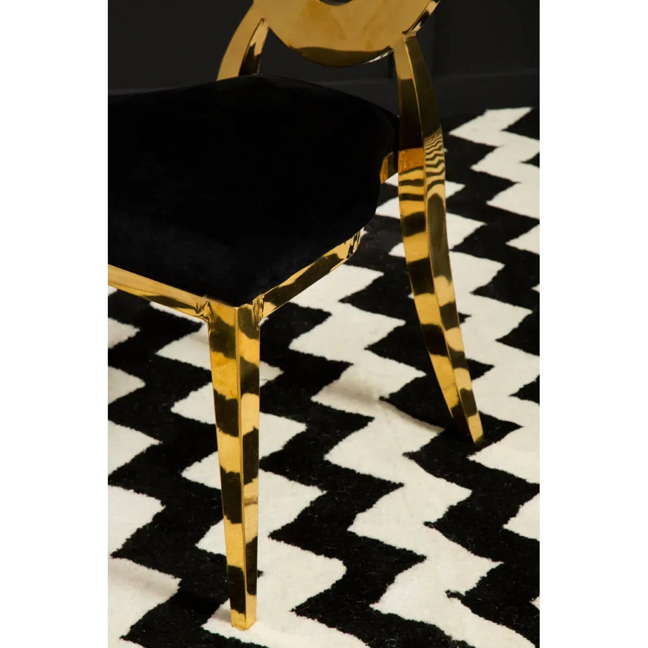 Gold dining chair with black velvet seat on geometric black and white rug