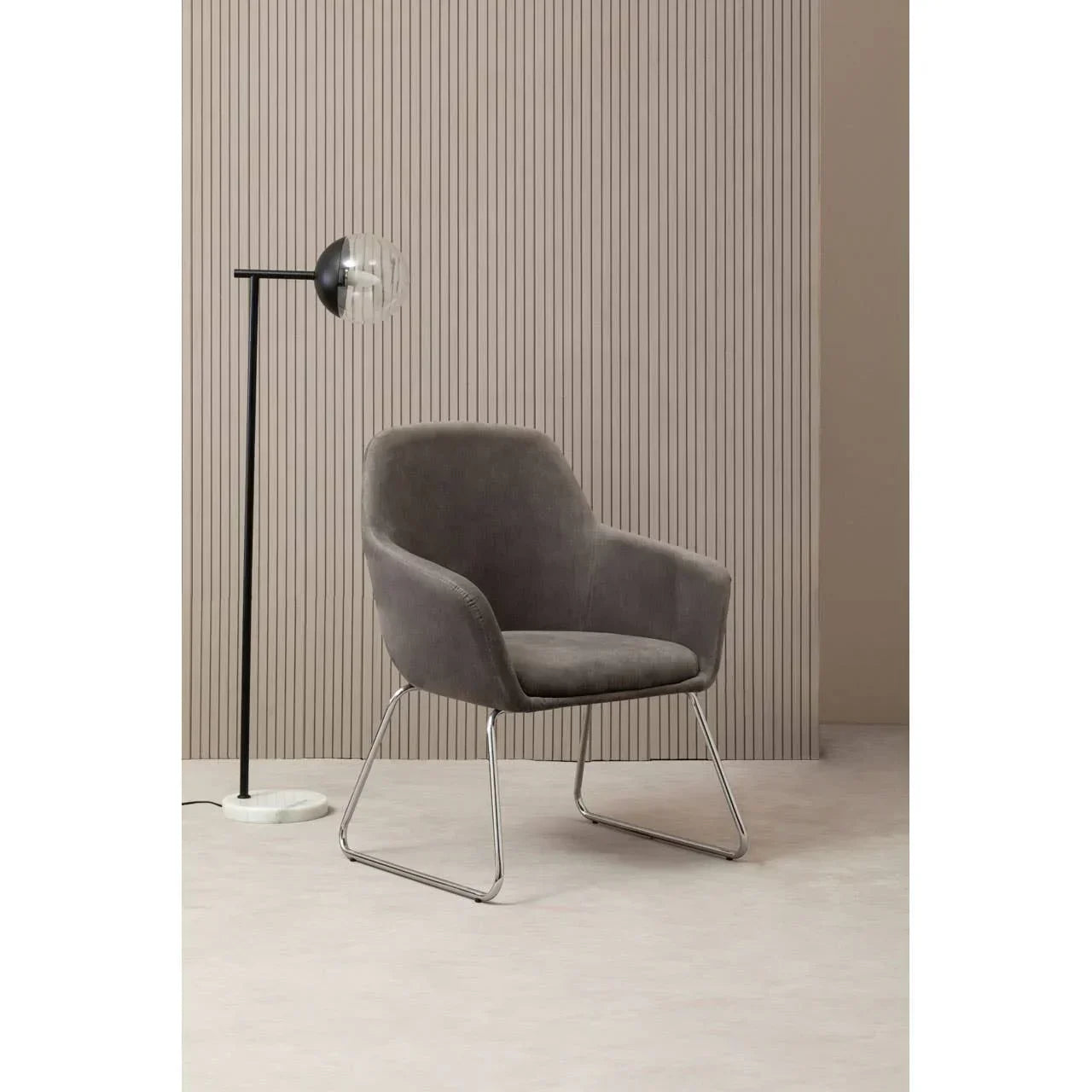 Grey upholstered accent chair with metal legs beside modern floor lamp