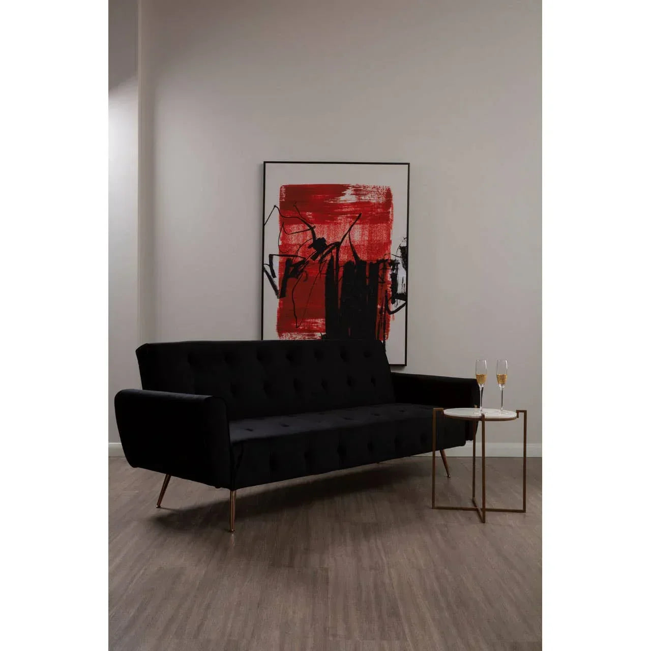 Black velvet sofa with gold legs beside marble side table and modern red wall art