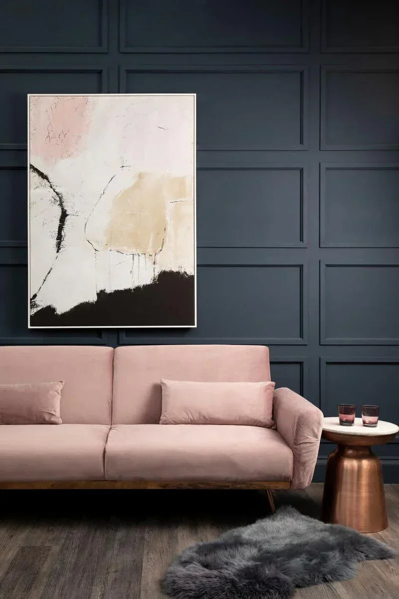 Blush pink velvet sofa with matching cushions, bronze side table and abstract wall art