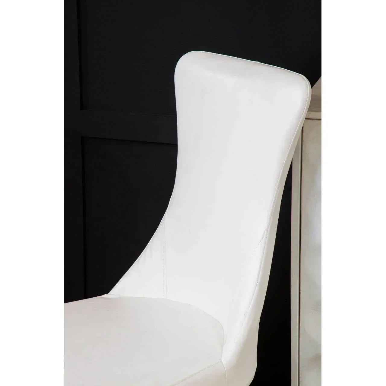 White leather dining chair with curved backrest against black panelled wall