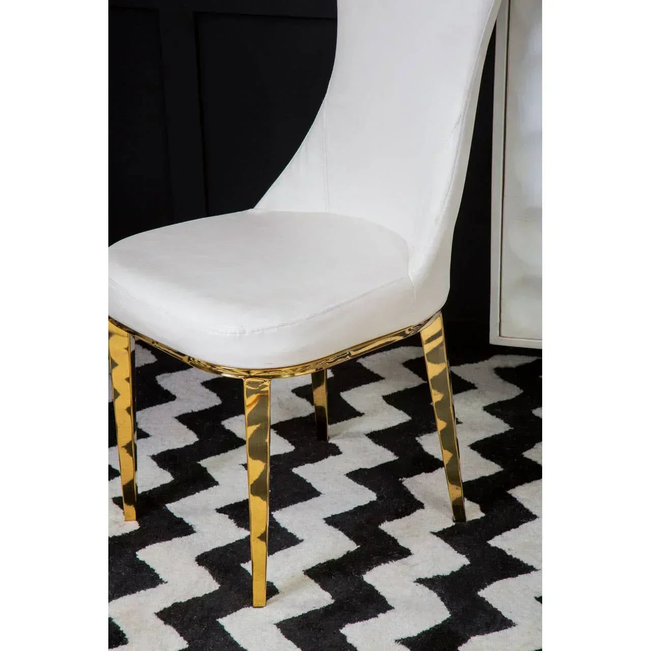 White dining chair with gold metal legs on black and white chevron rug