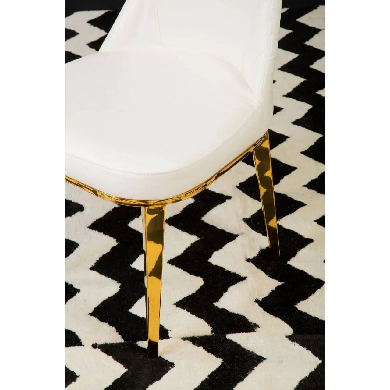 White dining chair with gold legs on black and white chevron rug