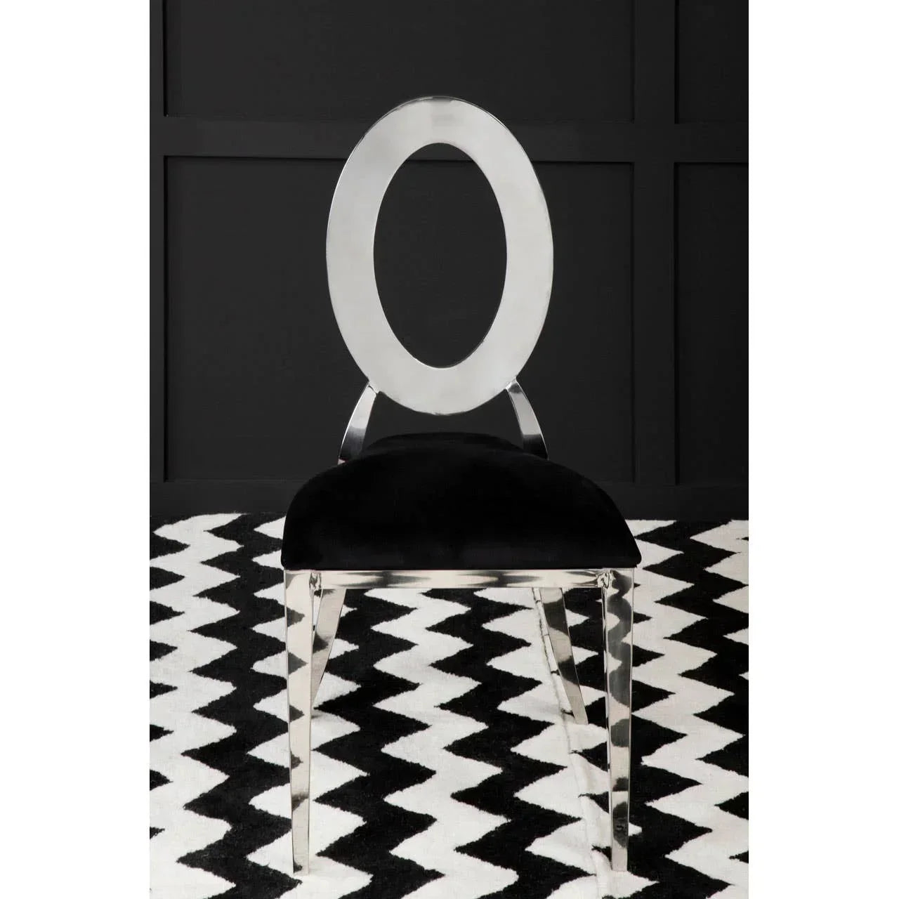 Modern dining chair with chrome oval backrest and black velvet seat on zigzag rug