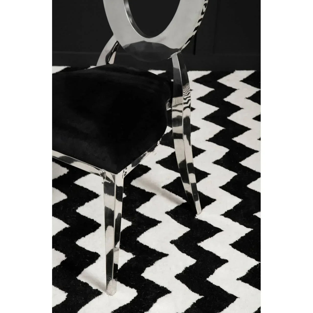 Black velvet dining chair with chrome legs on geometric black and white rug