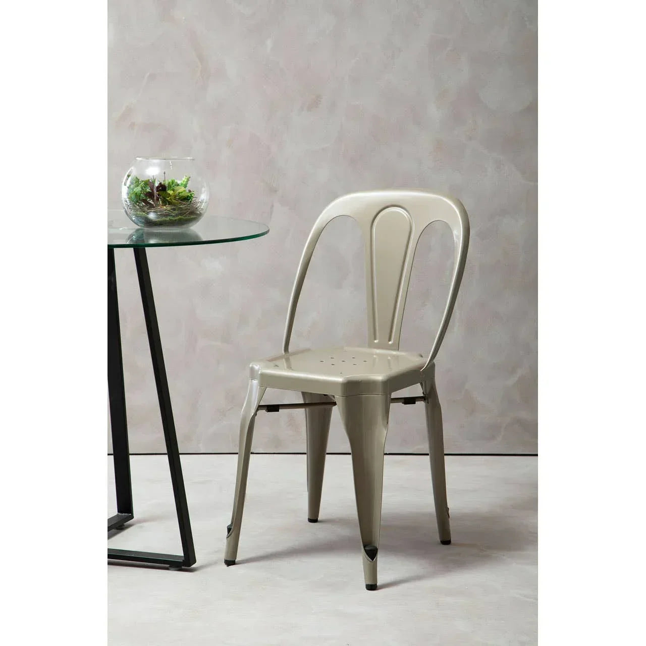 Beige metal dining chair beside round glass table with black leg
