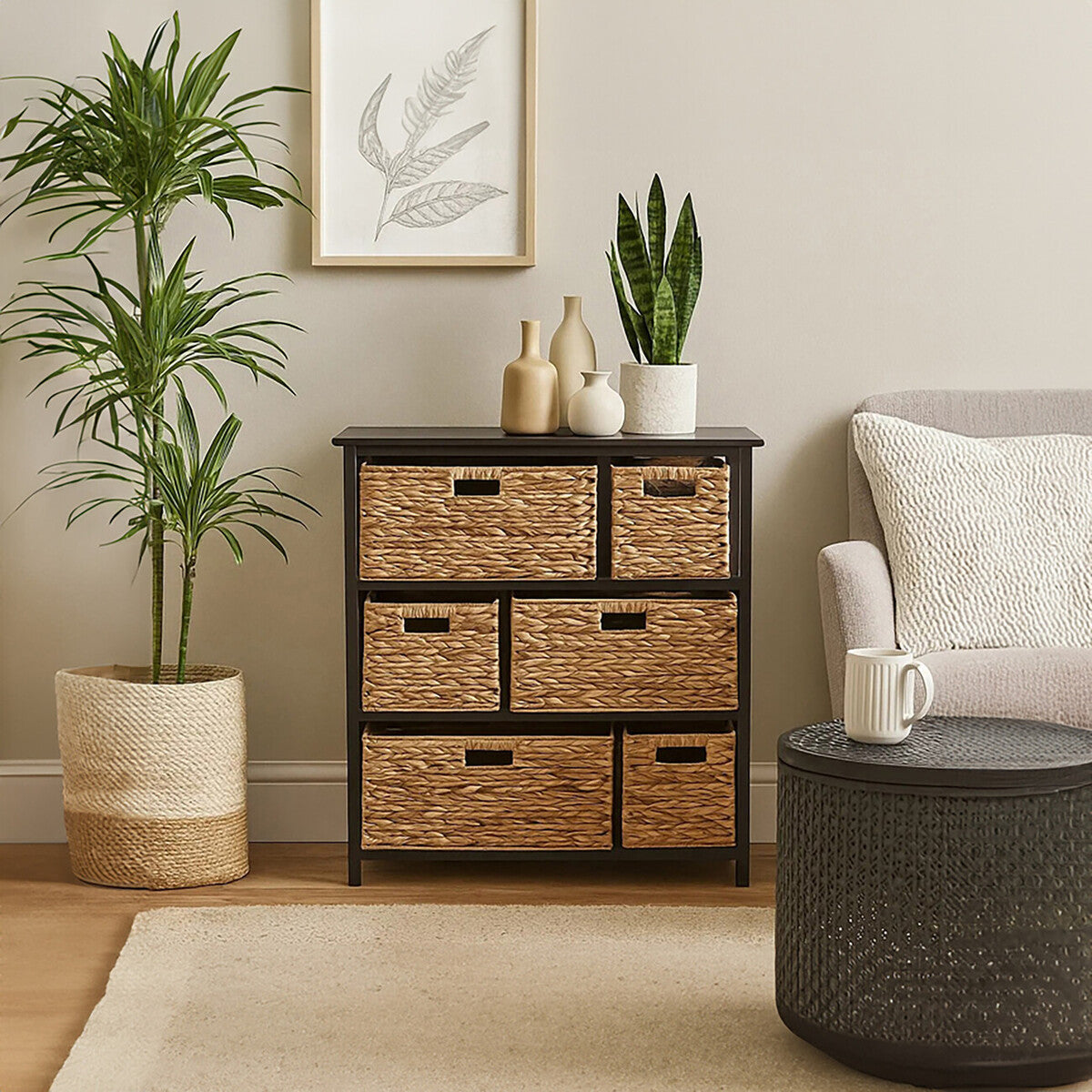 Black storage unit featuring six water hyacinth drawers, placed next to a light-colored sofa and a round coffee table. A potted plant and a framed artwork are visible in the background, enhancing the cozy living space ambiance