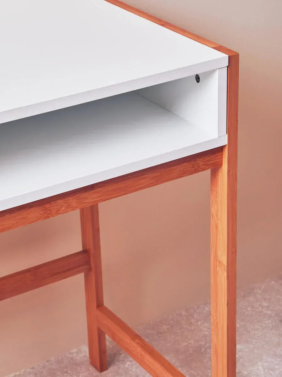 White desk with open storage shelf and wooden legs against beige wall