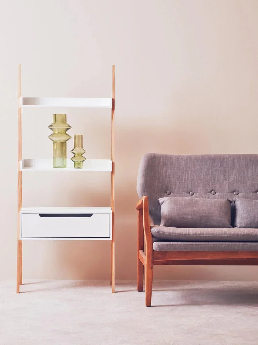 Modern wooden shelving unit with glass vases beside a grey fabric sofa in living room