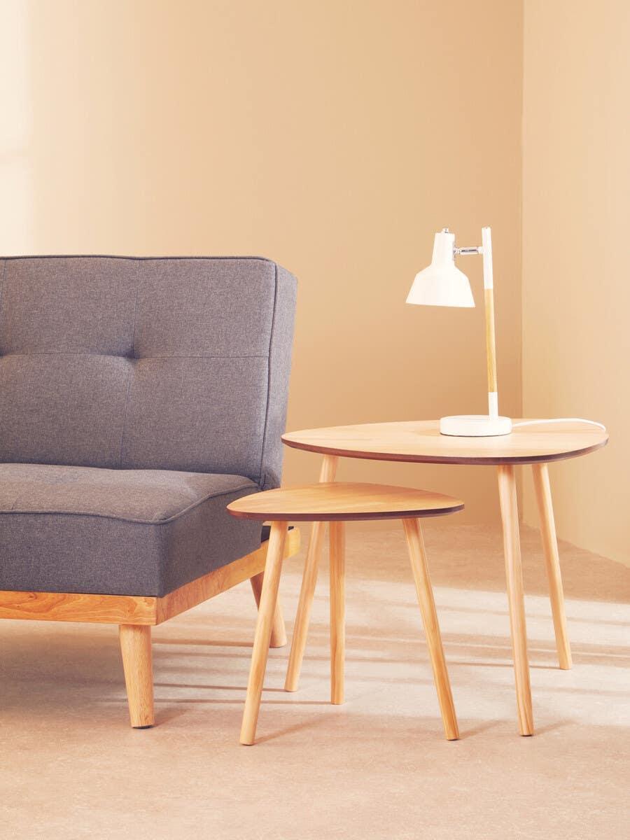 Grey fabric sofa with wooden legs beside nested oak side tables and white desk lamp