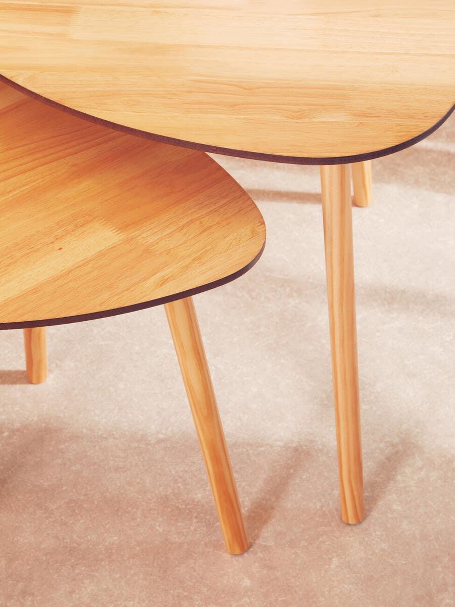 Set of two light wood coffee tables with rounded edges and angled legs on beige floor