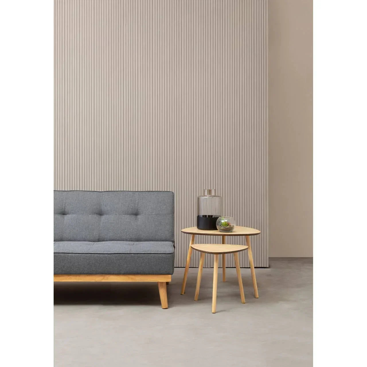 Grey fabric sofa with wooden frame beside two round nesting tables in modern living room