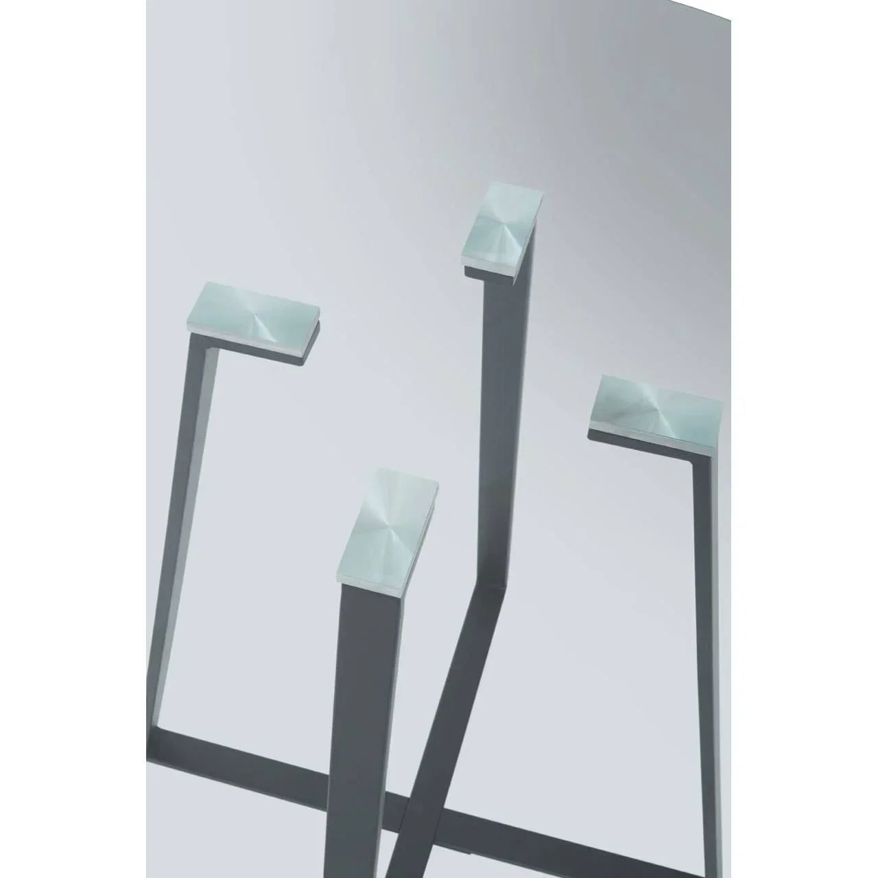 Closeup of brushed metal table legs with square tops against a plain background