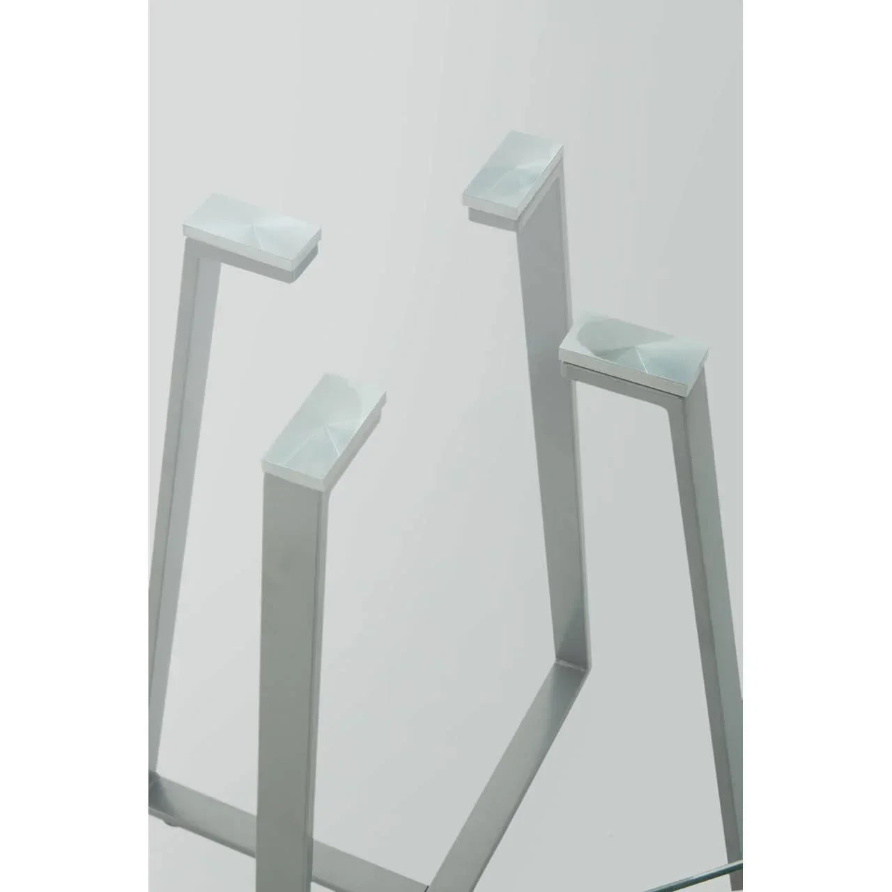 Close-up of modern glass table with silver metal legs and geometric supports
